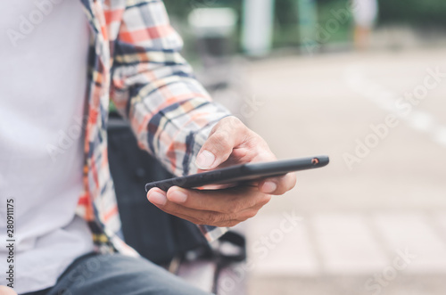 close up handsome man using hand typing mobile phones and touch screen working search with app devices outdoor in city with sunrise and building background. © thithawat