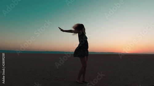 The young girl dances in the desert, at sunrise the sun.