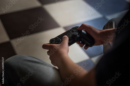 Child holds joystick while sitting on couch at home  playing video game on laptop computer
