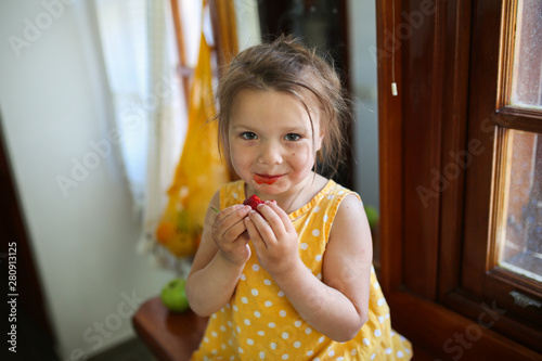 funny girl in yellow summer dress with strawberry