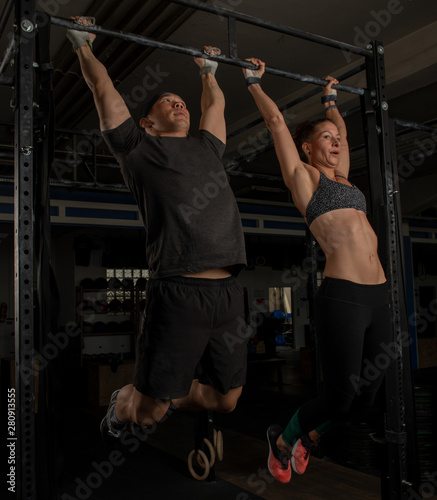 Schönes fittes Paar trainiert funktionelles Fitness. Der muskulöse Mann und die athletische Frau machen im Workout die Übung Zehenspitzen zum Reck.Sport mit dem Partner. Teamwork.