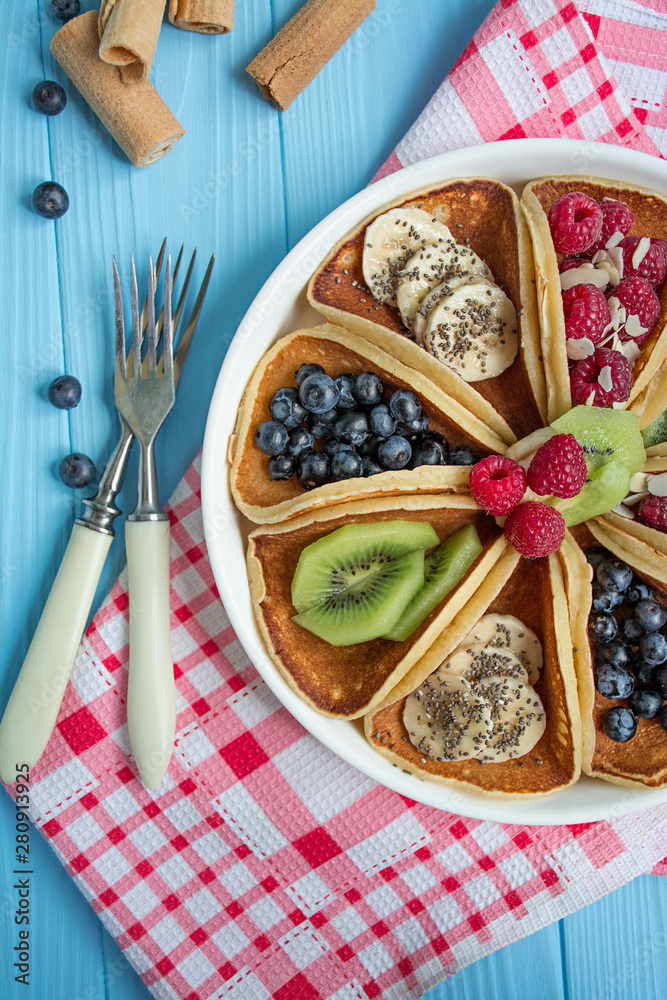 Classic American pancakes with fresh berry on a blue wooden background. Pancakes with fruit. Summer homemade breakfast.