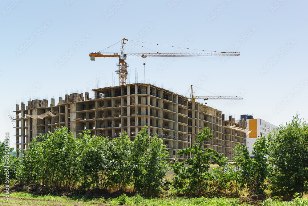 Construction of monolithic frame apartment building. The skeleton of the building and the tower crane against