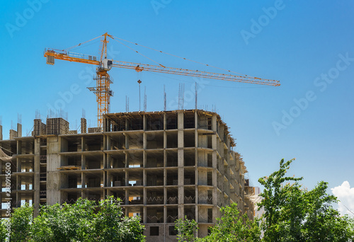 Construction of a monolithic frame of an apartment building consisting of columns and ceilings. The skeleton of the building and the tower crane against