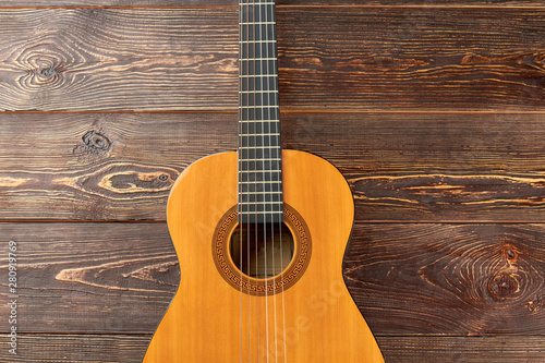 Acoustic guitar on dark wooden background. Ukulele on brown wooden surface. How to play country guitar.