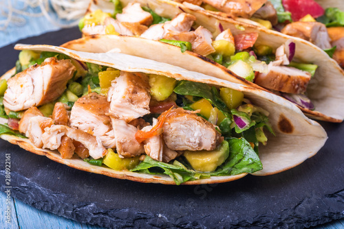 Tacos with vegetables, avocado and chicken breast on a slate dish - traditional mexican appetizer