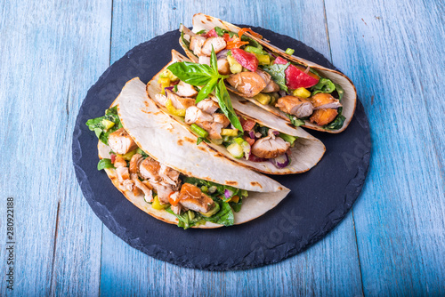 Tacos with vegetables, avocado and chicken breast on a slate dish - traditional mexican appetizer