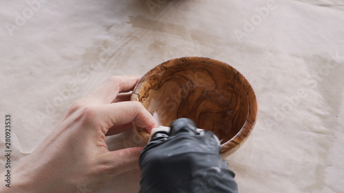 woodworker applying oil finish to olive wood bowl from above photo