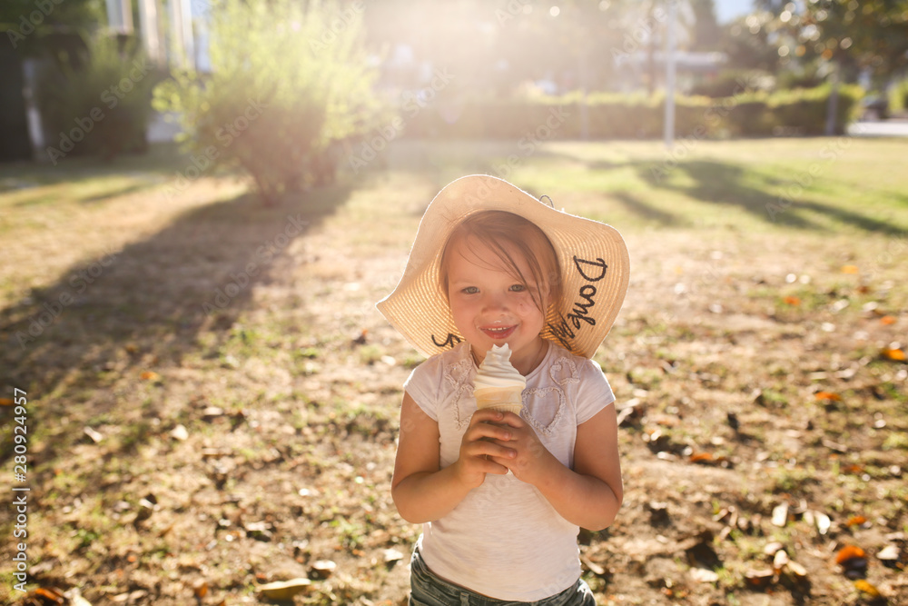 Obraz premium funny girl in wicker hat eats ice cream, close-up