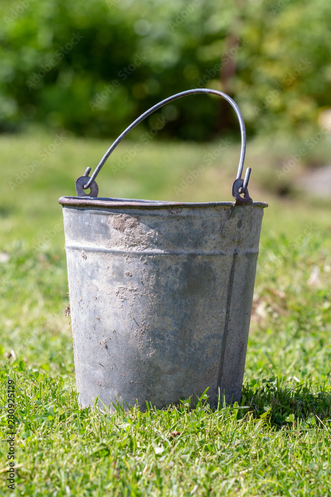 old metal bucket on the green grass of a garden lawn on a sunny summer day old metal bucket on the green grass of a garden lawn on a sunny summer day
