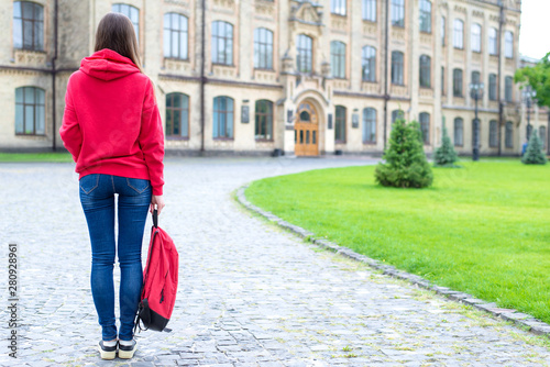 Back rear behind full length bosy size photo of serious confident concentrated hipster holding schoolbag in hand looking at the entrance standing near green lawn photo