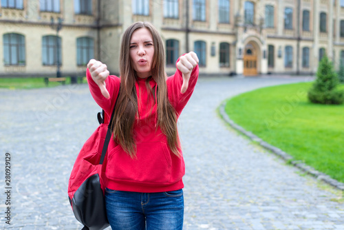 Photo of mocking unpleased whistling teen hipster in casual jeans and sweater sweatshirt giving fingers down