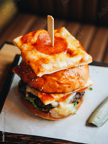 Big burger with beef cutlet, white bun and pepperoni pizza
