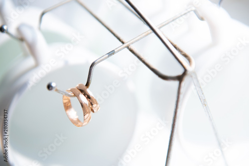 wedding rings and white glasses hanging on the hook from the stand for cups and plates © Makulov