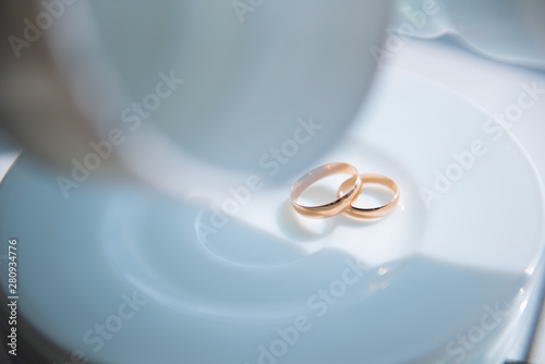 wedding rings on a white plate that lie in a stack on a stand with hanging white circles
