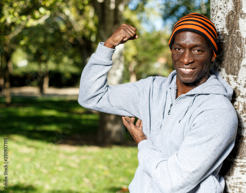 Active african american young man standing near tree before training in park