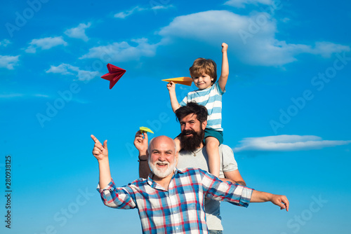 Men generation: grandfather father and grandson are hugging looking at camera and smiling. Father and son enjoying outdoor. Family people.