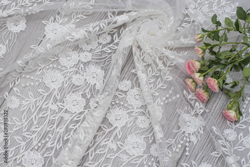 White wooden background with white spring flowers roses and lace ribbon. Happy womans day. The texture of lace on wooden background.