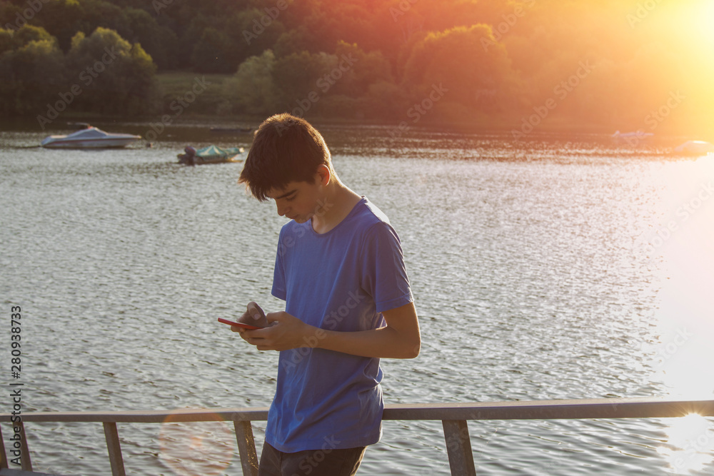 young man with mobile phone at sunset outdoors