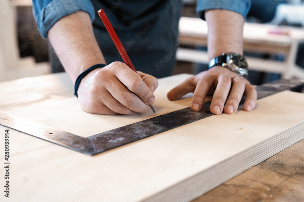 Carpenter working on woodworking machines in carpentry shop. A man works in a carpentry shop. Carpenter working on woodworking machines in carpentry shop. A man works in a carpentry shop.