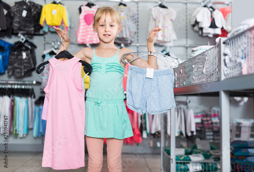 Portrait of girl choosing colored dress and wear in the shop