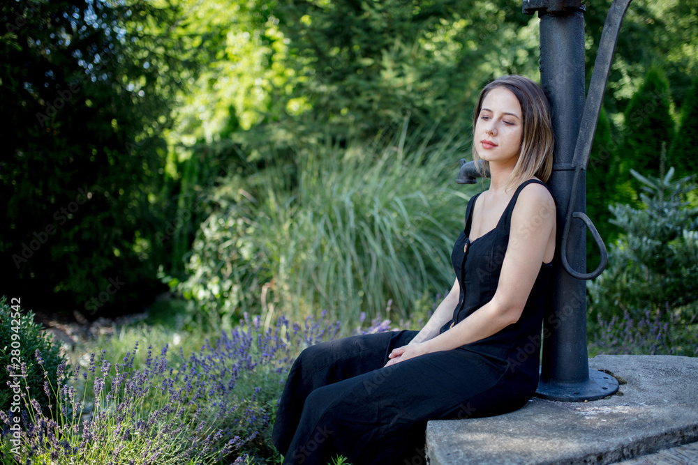 Young woman in dark dress sitting near lavender flowers Young woman in dark dress sitting near lavender flowers