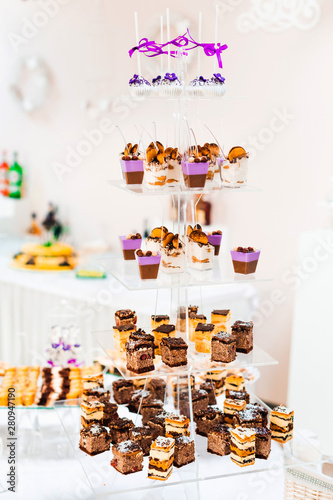 multilevel transparent stand with pieces of cake and cupcake.