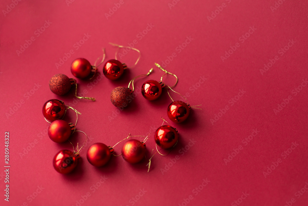 Red Christmas tree decorative toy balls on red celebratory Christmas background laid out in the shape of a heart. New Year's holidays. Christmas holidays Red Christmas tree decorative toy balls on red celebratory Christmas background laid out in the shape of a heart. New Year's holidays. Christmas holidays