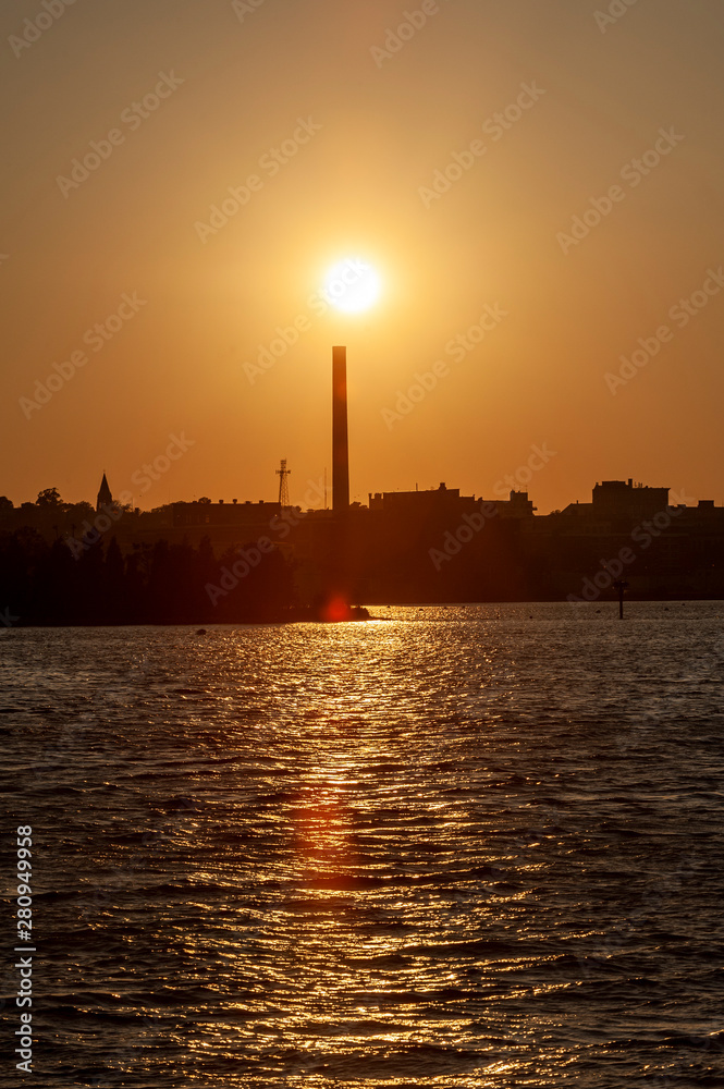Obraz premium Setting sun over smokestack at decommissioned New Bedford Gas and Edison Light Complex