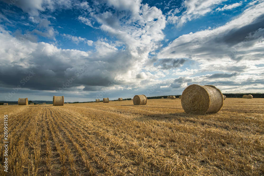 Bales of straw in the fields at harvest time with beautiful cloudy sky, Cornwall, UK