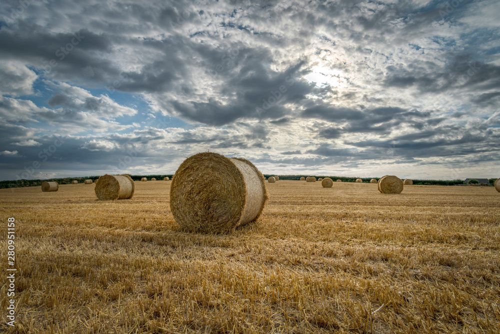 Bales of straw in the fields at harvest time with beautiful cloudy sky, Cornwall, UK