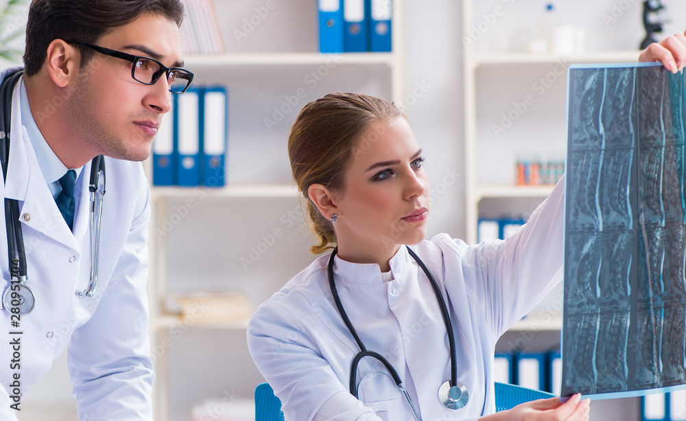 Two doctors examining x-ray images of patient for diagnosis Two doctors examining x-ray images of patient for diagnosis