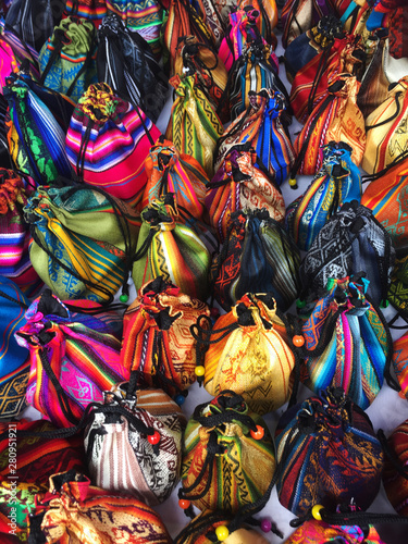 A table full of pouched in many different colours with south american patterns
