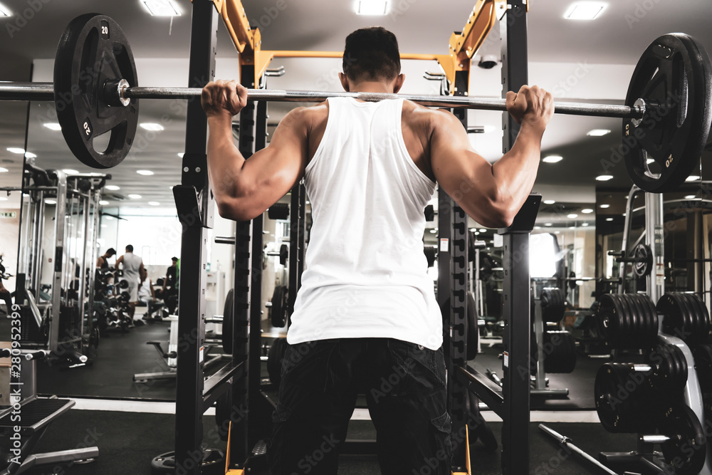 Fototapeta premium Man at the gym. Execute exercise squatting with weight, in gym