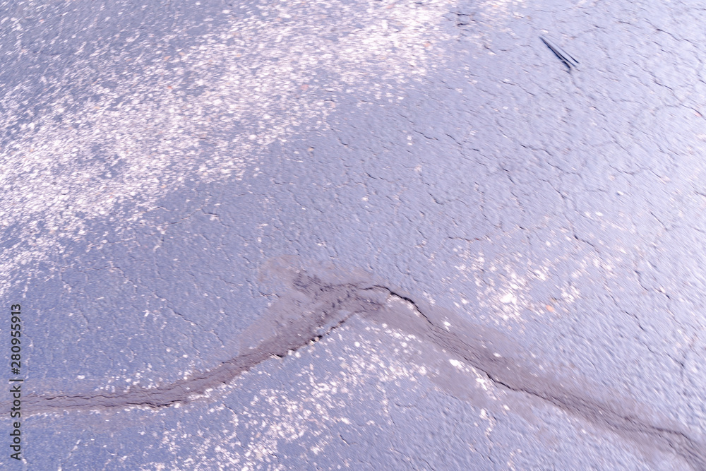 Tar patching cracks in asphalt pavement. Focus is on the tar in at the bottom.