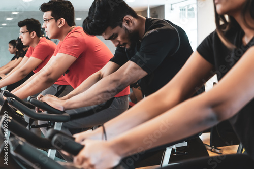 Fit people working out at spinning class in gym