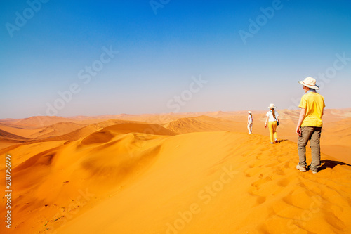 Family climbing up red sand dune