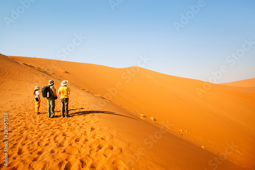 Family climbing up red sand dune © BlueOrange Studio