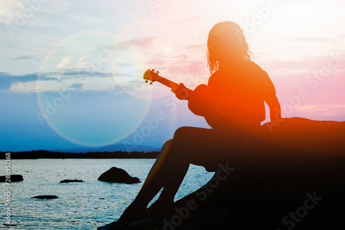 Konstfotografi happy girl with ukulele by the sea on nature silhouette background