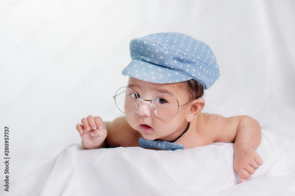 portrait of asian infant baby boy with blue cap and glasses on with white cloth background portrait of asian infant baby boy with blue cap and glasses on with white cloth background