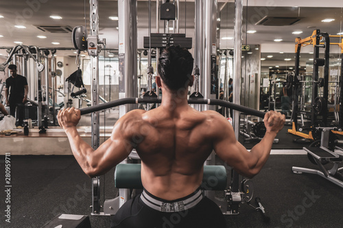 Fit man on lat pulldown machine at the health club. Work out on Pulldown Weight Machine