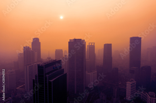 Silhouette of skyscrapers with dust smog at sunset