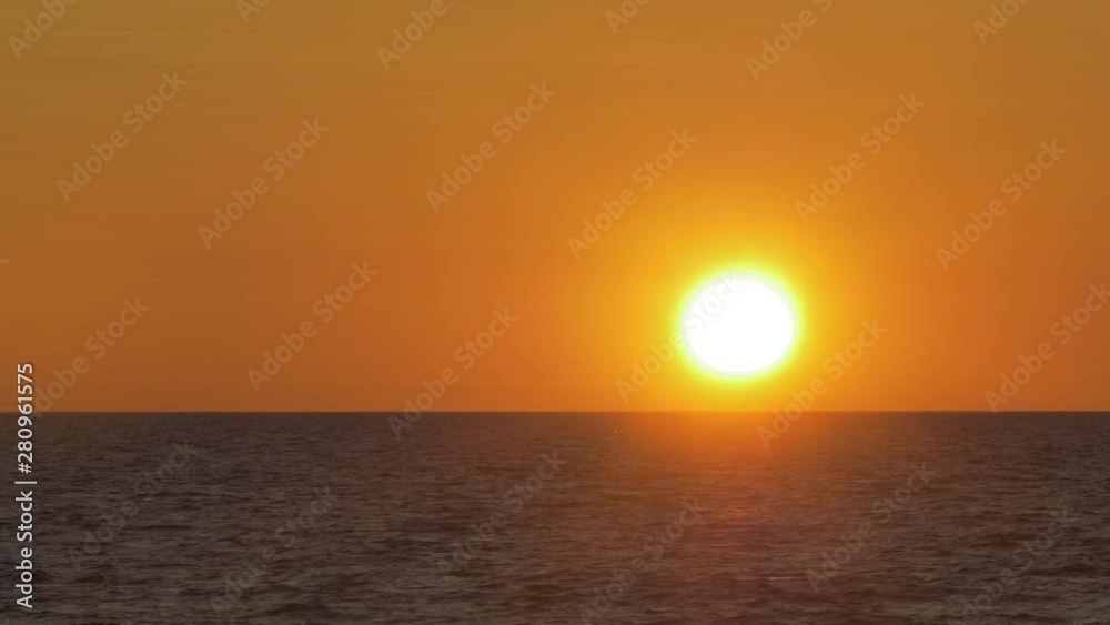Romantic sunset over the calm Baltic sea, big red Sun sets over the horizon in summer, medium shot from a distance