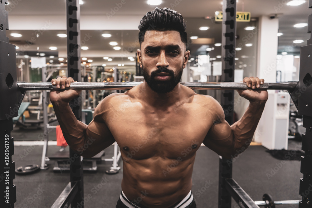 Man at the gym. Execute exercise squatting with weight, in gym Man at the gym. Execute exercise squatting with weight, in gym