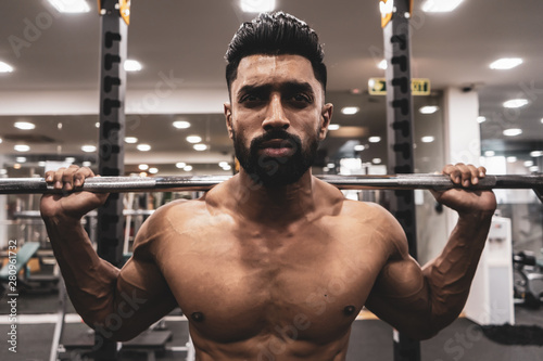 Man at the gym. Execute exercise squatting with weight, in gym photo