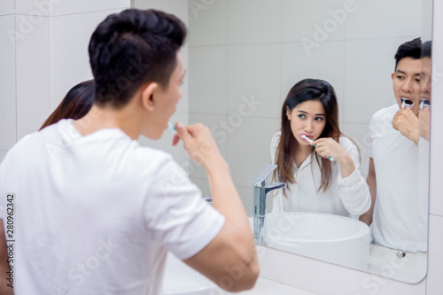 Young couple brushing teeth together in bathroom
