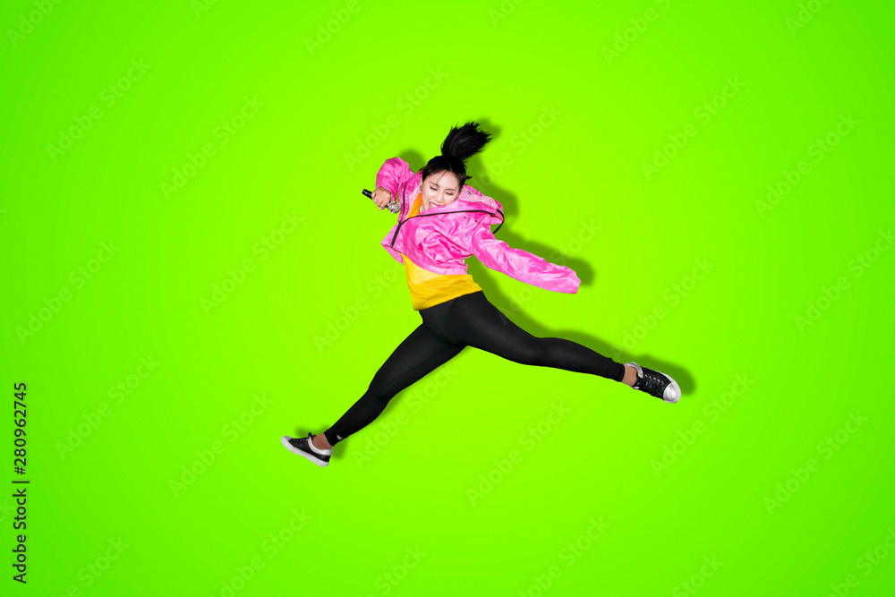 Young woman singing and jumping on studio