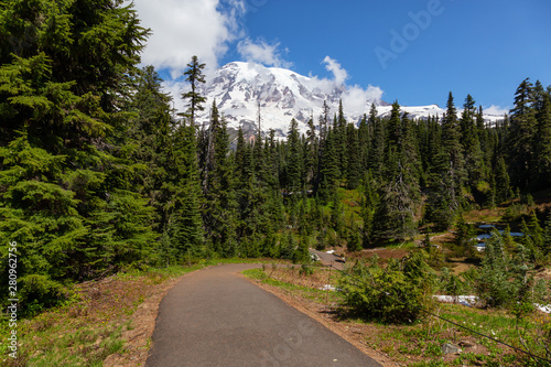 Beautiful view of a trail and a bridge over the river surrounded by the Mountain Landscape during a sunny summer day. Taken in Paradise, Mt Rainier National Park, Washington, United States of America.