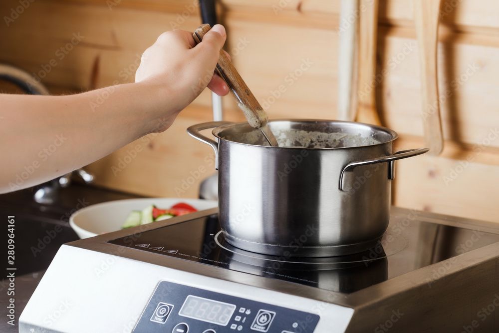Boiling soup in pan on electric stove in the kitchen