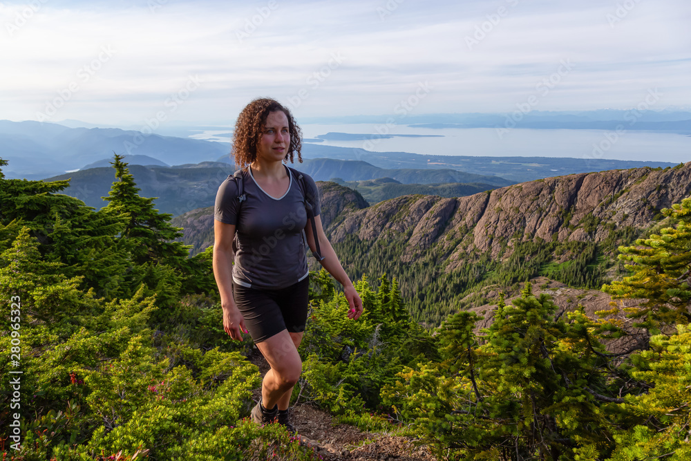 Adventurous girl hiking the beautiful trail in the Canadian Mountain Landscape during a vibrant summer evening. Taken at Mt Arrowsmith, near Nanaimo, Vancouver Island, BC, Canada.